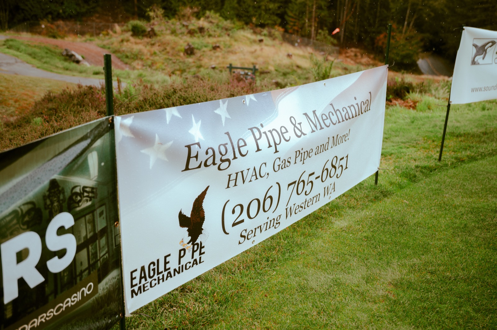 An Eagle Pipe & Mechanical sponsor banner staked along a fairway at the 7 Cedars golf course