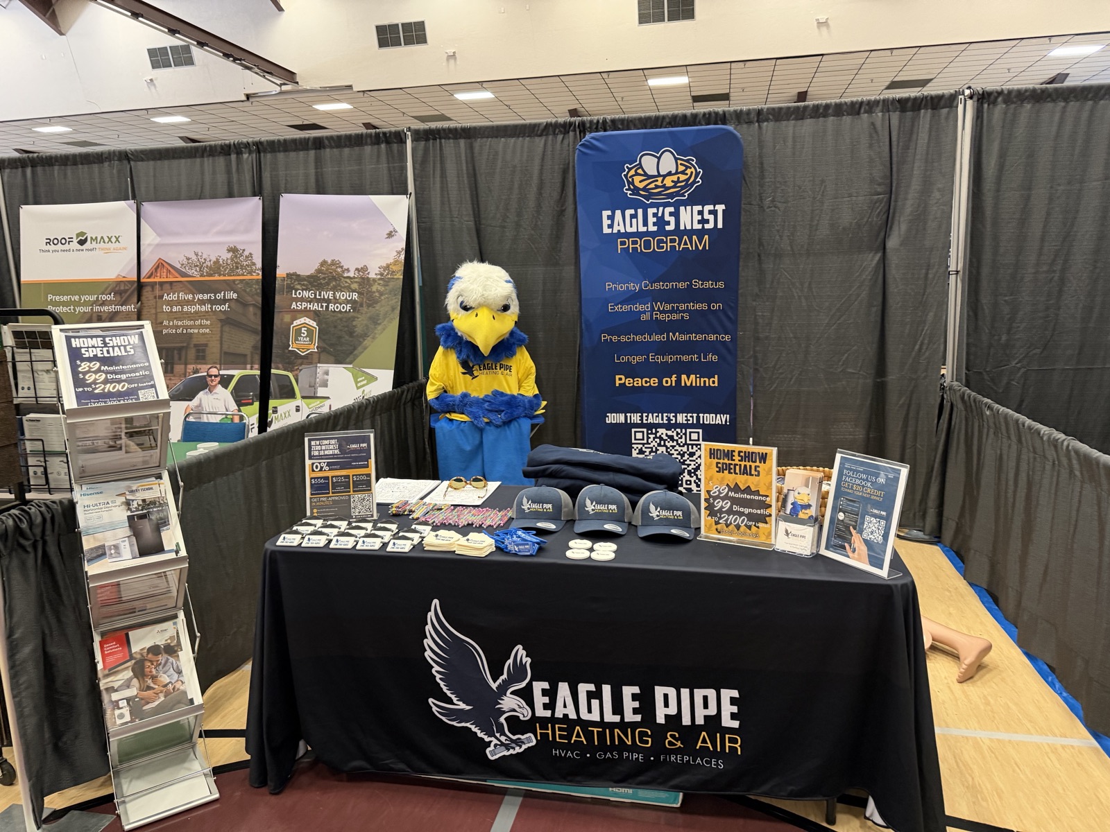 The Eagle Pipe home-show booth with the Eagle's Nest Program banner, branded hats and giveaways, and the company mascot behind the table