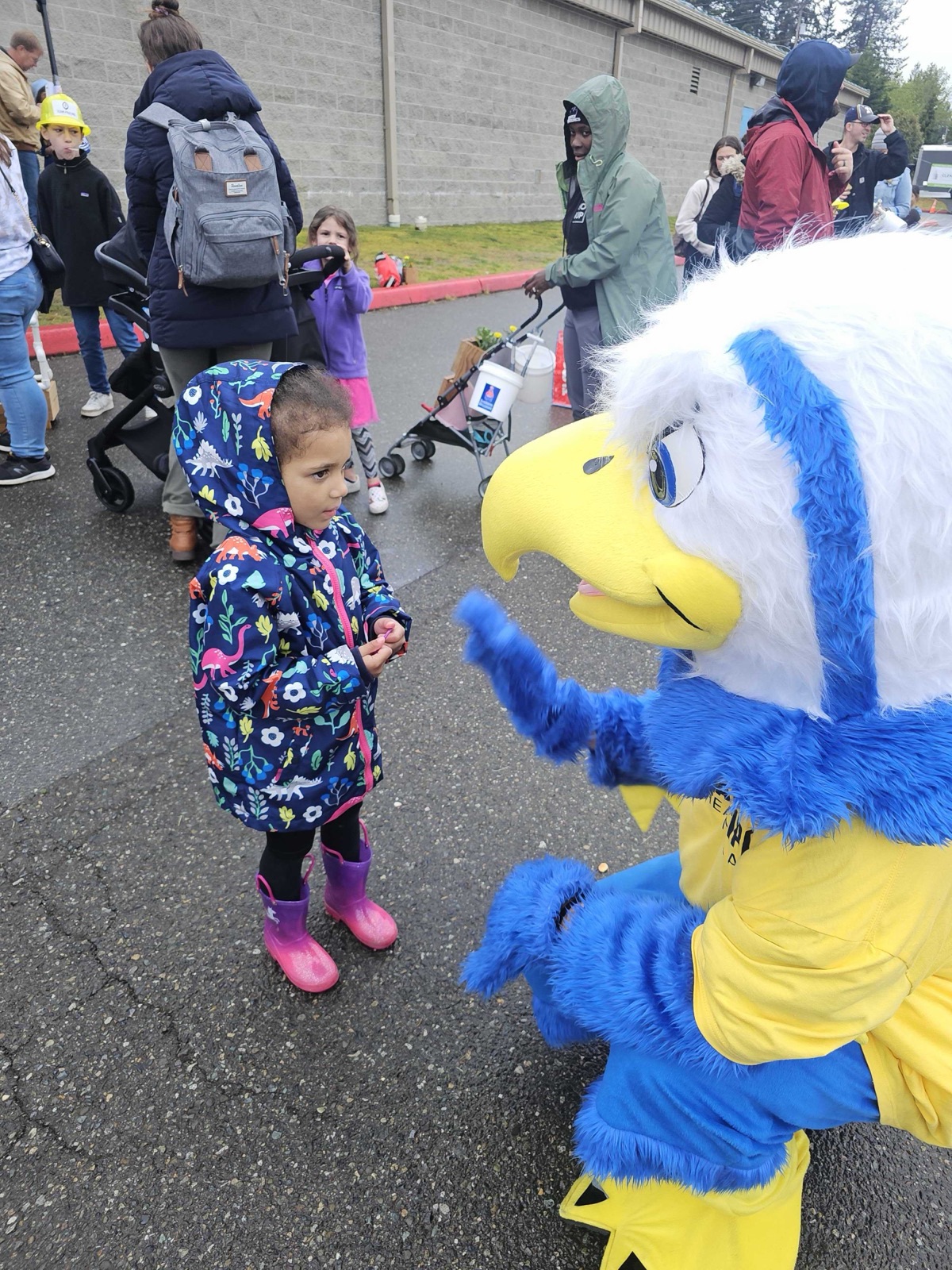 The Eagle Pipe mascot greeting a young child at an outdoor community event